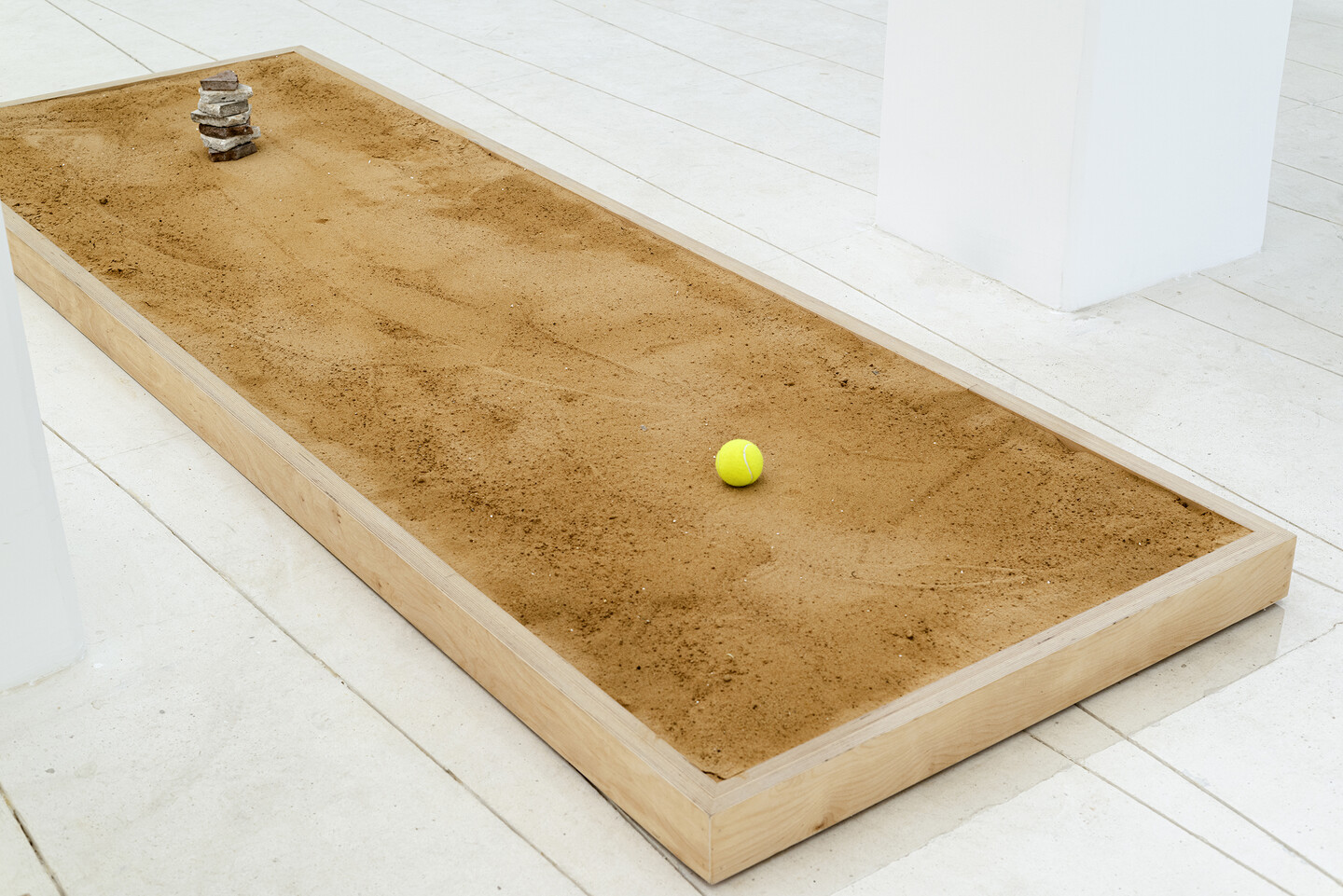 Seven Stones, 2024, 7 stones, tennis ball, sand, wood, 300 &times; 100 &times; 10 cm